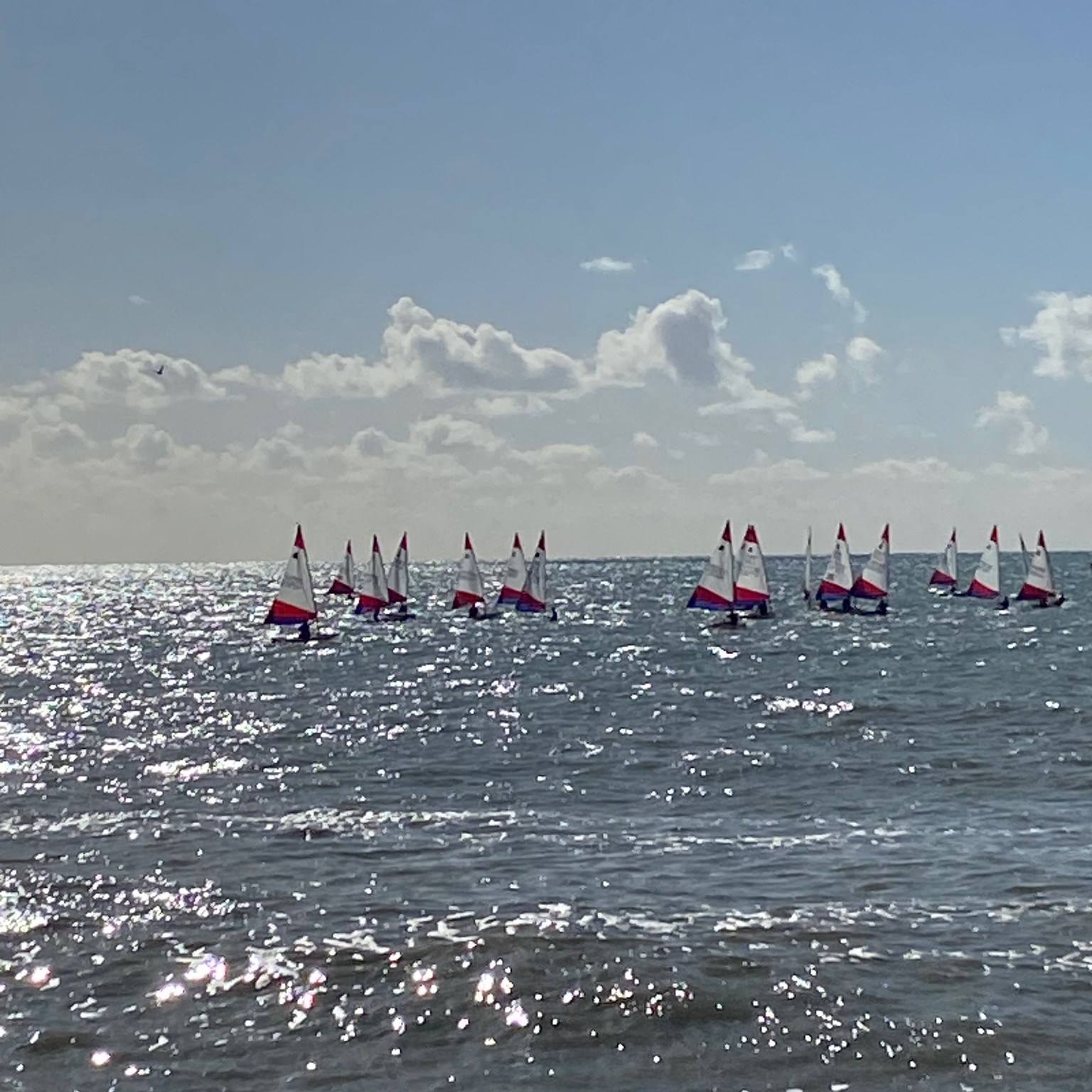 Bright, sunny day with view of a cluster of sailboats in the distance in the English Channel. 