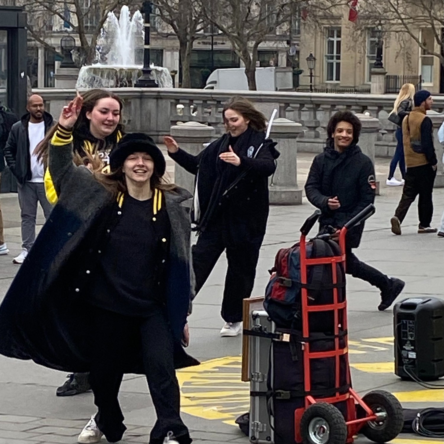 Jubilent teenagers dressed in black, dancing in Trafalgar Square London.