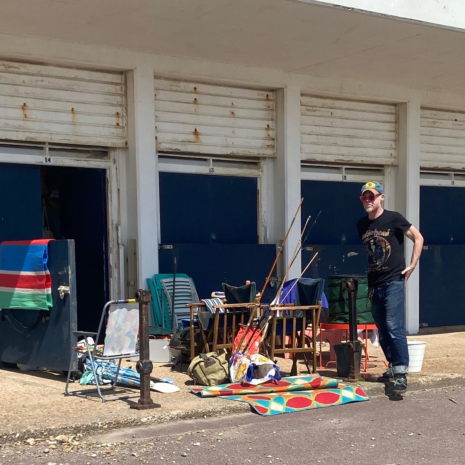 Young guy with all his fishing gear displayed outside a hut along English Channel.