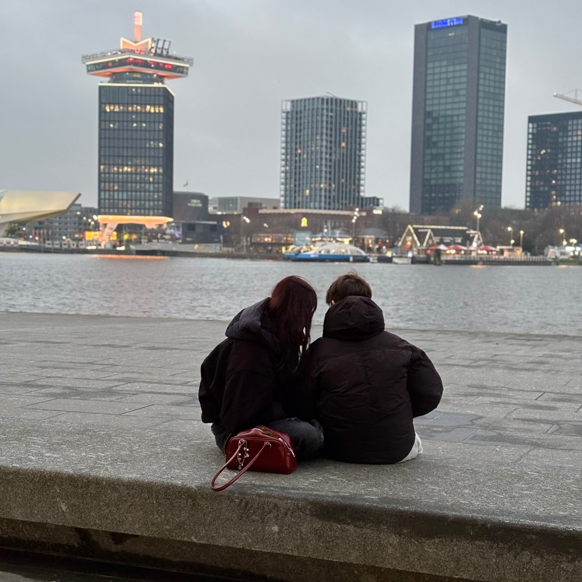 Silhouette of young couple sitting and looking at Amstel River